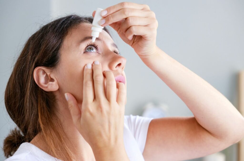 Woman using eye drops, managing dry eye symptoms that may contribute to headaches.