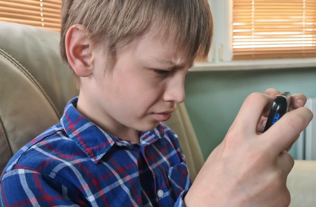 A child holds their tablet close to their face and still needs to squint to see it clearly.