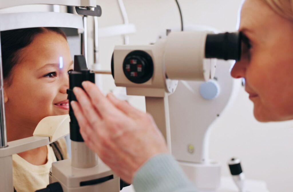A younger child sits as the eye doctor examines their eyes.