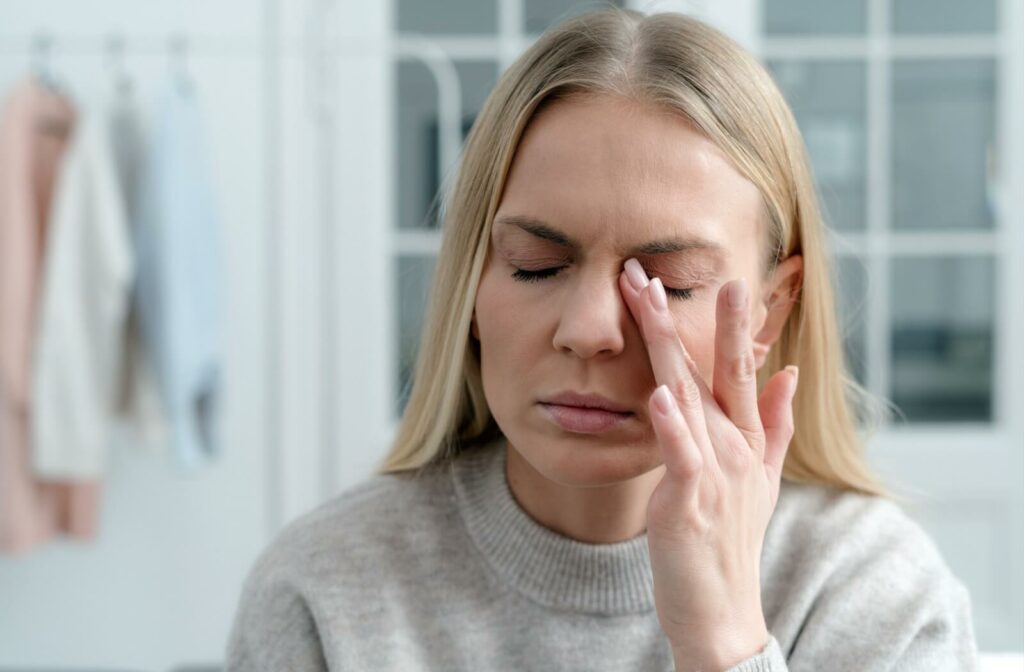 A person gently rubbing her closed eye, appearing to experience irritation or discomfort, possibly from dry eyes or eye strain.